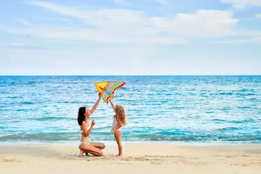 Madre e hija volando una cometa en la playa