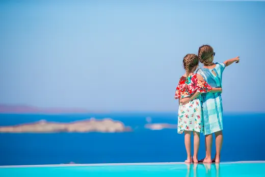 Dos niñas pequeñas al borde de la piscina mirando al mar